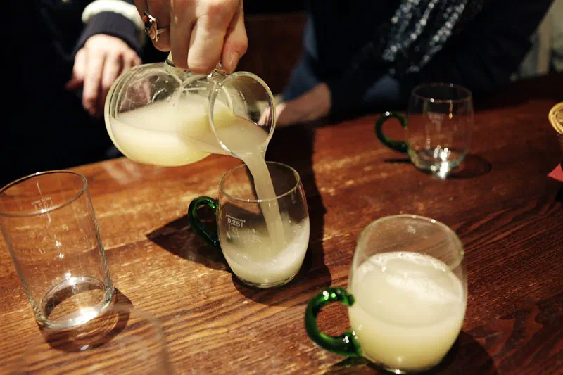 Trüber Federweißer wird aus einem Krug in ein Glas gegossen