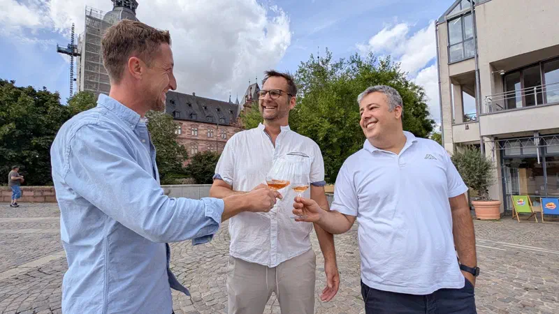 Veranstalter des Vinum Culinarium mit Weingläsern vor Schloss Johannisburg