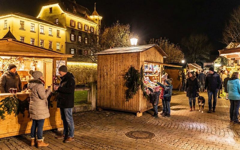 Treuchtlinger Schlossweihnacht: beleuchtetes Stadtschloss und Weihnachtsmarktbuden rund um den Schlossgraben