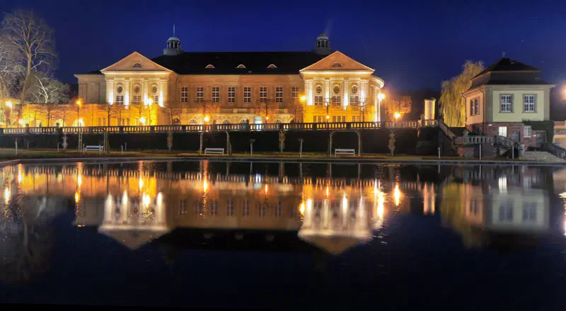 Beleuchteter Regentenbau in Bad Kissingen mit Spiegelung im Wasser