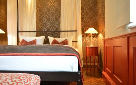 Individuell gestaltetes Zimmer mit gemusterter Wand und Himmelbett in der Villa Mittermeier