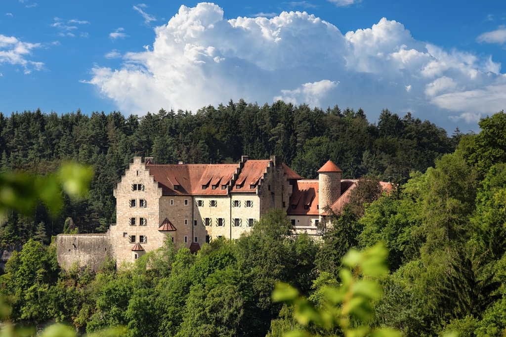 Burghotel Franken: historische Burg bei Abenddämmerung mit Türmen und Weinbergen