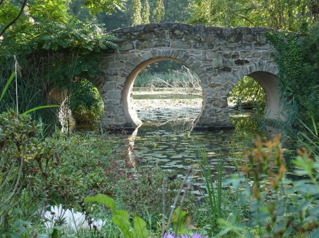Steinerne Rundbogenbrücke über einen Weiher im Schlosspark Dennenlohe